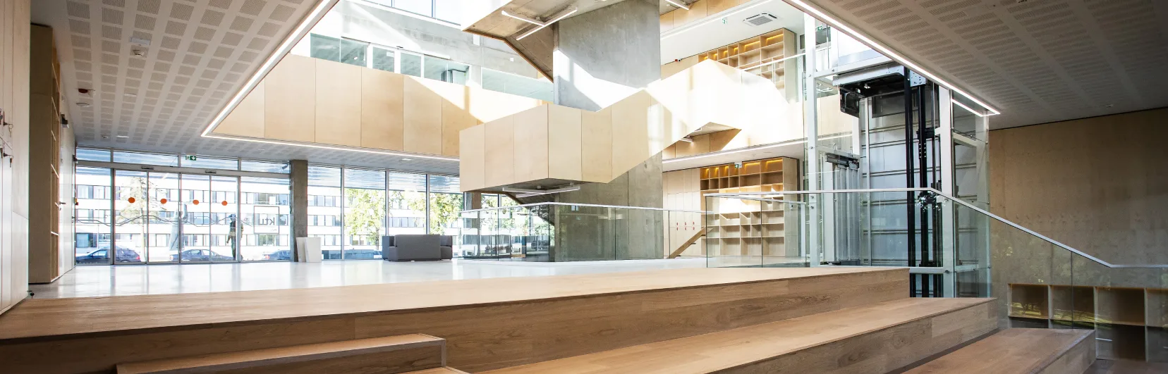 What makes the Centre unique Modern university interior featuring a spacious atrium, wooden steps, glass railings, a glass lift and contemporary architectural elements.